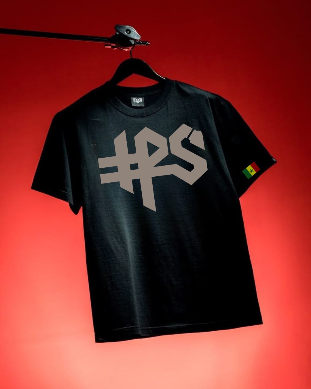 T-shirt noir HPS suspendu sur fond rouge